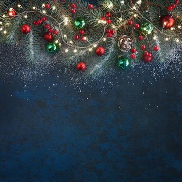Christmas background with fir twigs, red berries, cones and Xmas lights on dark, copy-space