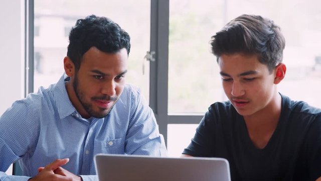 High School Tutor Giving Male Student One To One Tuition At Desk 