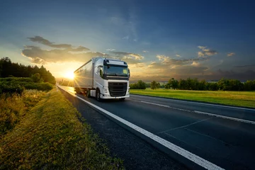 Foto op Aluminium White truck driving on the asphalt road in rural landscape in the rays of the sunset © am