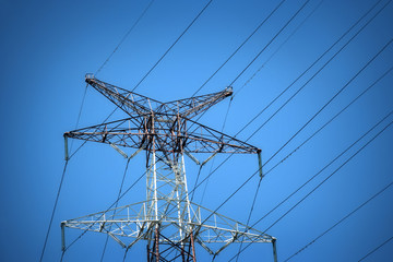 Close up metal tower of Power Lines over blue sky