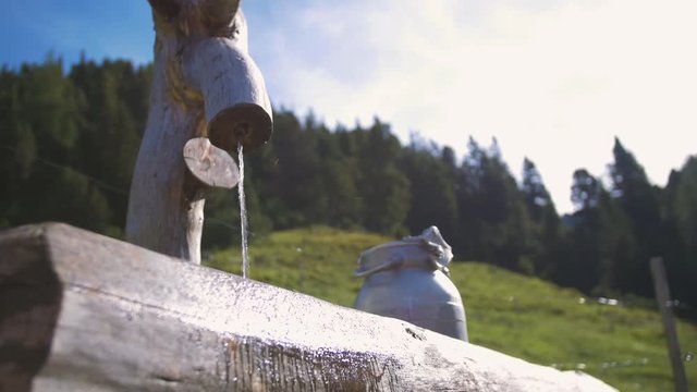 Idyllic mountain scenery with a wooden standpipe and a milk can
