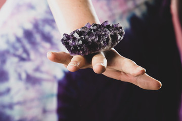 Hands holding purple amethyst crystal