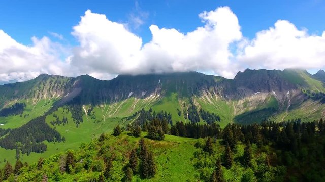 Aerial shot over Alpine landscape, Switzerland in spring
Forest and Alpages, summits in the background in the clouds
