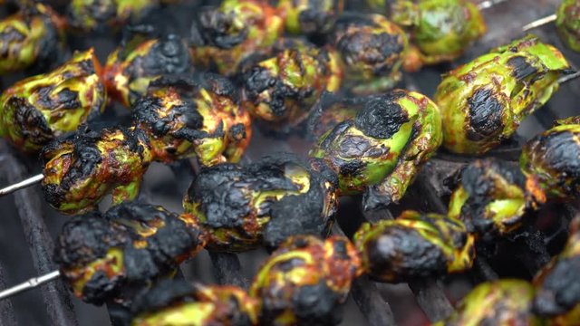 Closeup of skewered, smoking, brussels sprouts roasting on a hot grill.