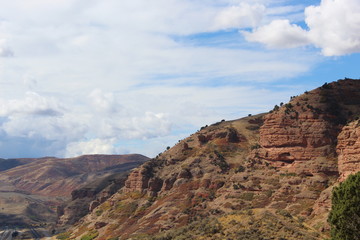 red and grey rock faced desert hillsides of Utah , partly cloudy skies.
