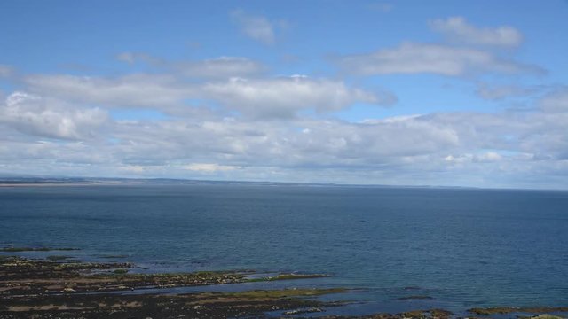 Time-lapse showing rolling clouds over the sea near a rock coast. Filmed looking out over St Andrews Bay, Scotland.