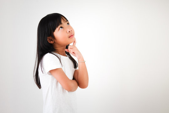 Cute Asian Child Girl Cross One's Arm And Looking Up. She Is Using The Idea To Find Something To Do