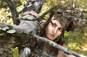 woman in a suit of felt and make-up of natural remedies and forest debris, the Dryad hides in an...