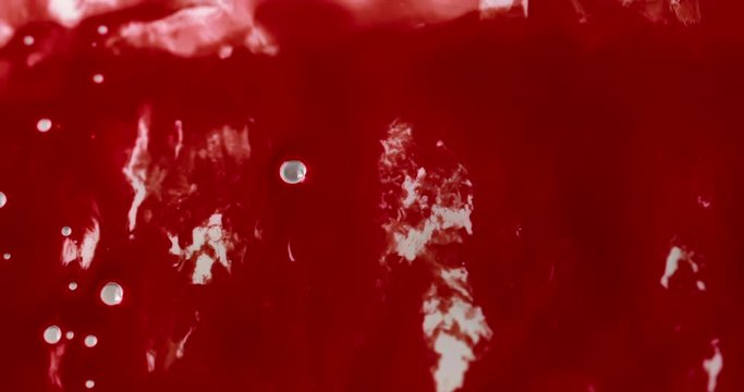 Sticky red gooey liquid resembling blood oozes down a viscous white surface with a few bubbles. 4K