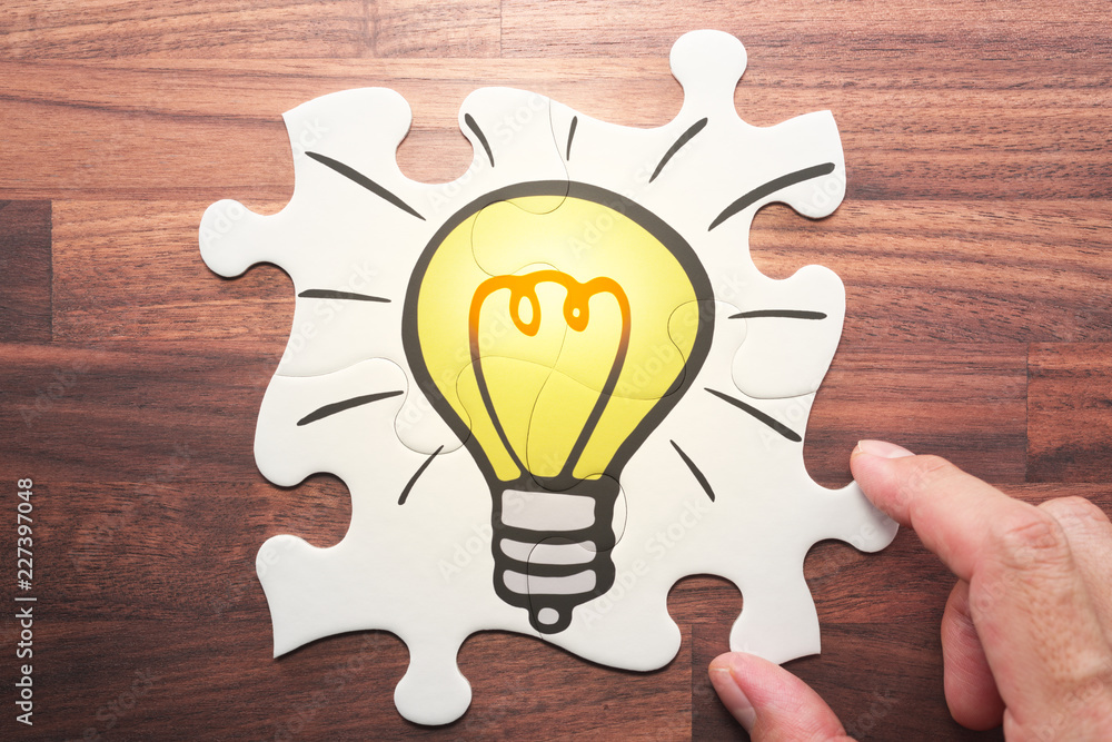 Aufkleber Idea creation concept. Solving problem with creative and innovative combination. Solving lightbulb jigsaw puzzle on wood desk.