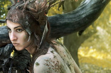 woman in a suit of felt and make-up of natural remedies and forest debris, the Dryad hides in an...