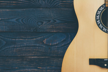 Acoustic guitar lies on a wooden textured background.