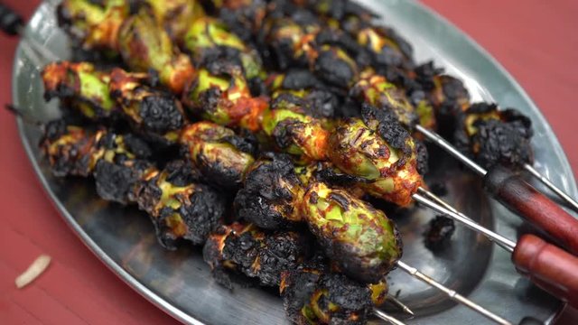 Turning view of brussels sprouts skewered on a silver platter.
