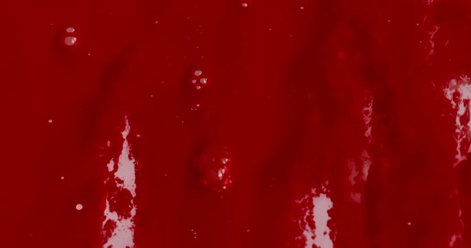 Heavy flow of sticky red gooey liquid resembling blood sliding down a viscous white surface with a few bubbles. 4K