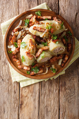 Cepelinai zeppelins or didzkukuliai is a traditional Lithuanian dish of stuffed potato dumplings close-up. Vertical top view © FomaA