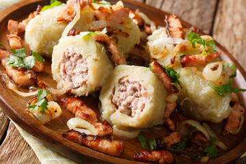 Delicious Lithuanian potato dumplings with meat served with bacon and fried onions close-up on a plate. horizontal © FomaA