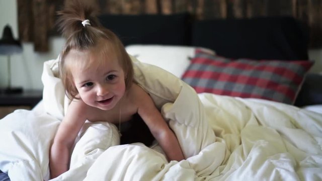 Cute little baby girl on bed at home