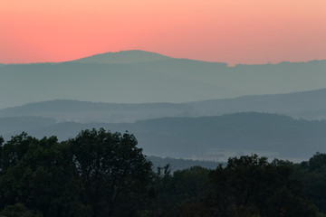 Red sunset sky with hills tree silhouette