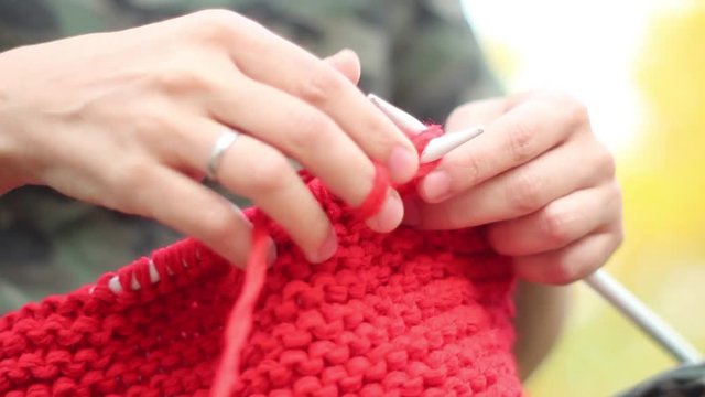 Woman knits outside, short plane.