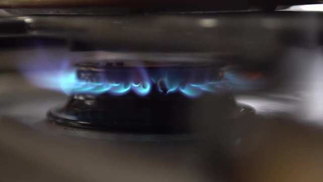 Close up shot of stove flame heating, boiling, a pot or pan