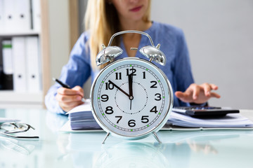 Close-up Of An Alarm Clock On Reflective Desk