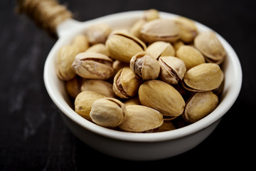 white bowl full of delicious pistachios on an old black table in a pub