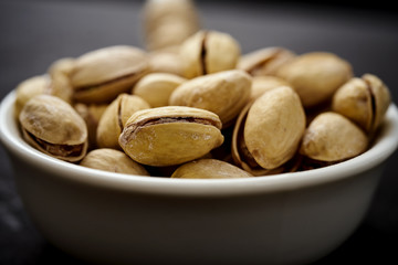 white bowl full of delicious pistachios on an old black table in a pub