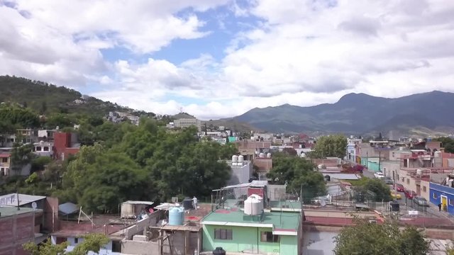 Ascending aerial shot, panning up over Oaxaca City in Oaxaca, Mexico on a sunny day.