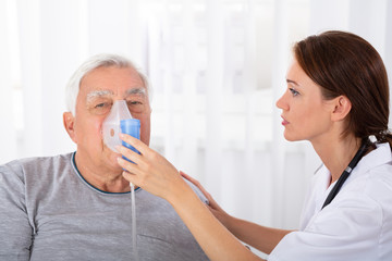 Doctor Holding Oxygen Mask Over Man's Face