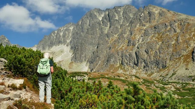 Older female hiker stopping to rest and take in the view of  the Gerlachovsky kotol. (high tatra, slovakia)