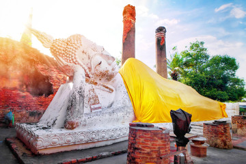 Big white cement buddha statue wearing a yellow coat and pagoda with sunlight at Wat Yai...
