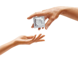 Man's hand giving condom to woman's hand isolated on white background. Close up. High resolution...