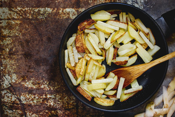 Fried potatoes in a black frying pan top view