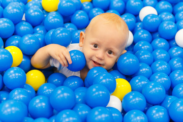 Fototapeta na wymiar Charming baby of 10 months in a pool of plastic balls