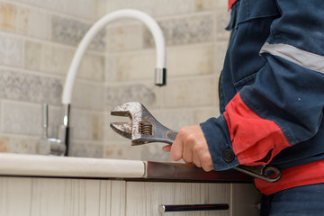 Plumber repairing tap at kitchen. plumber fixing a sink.Plumber man with tools in the kitchen....