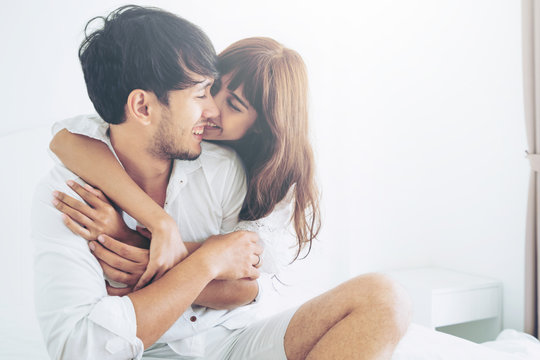 Happy Young Couple Relaxing In Home Bedroom After Waking Up In The Morning.