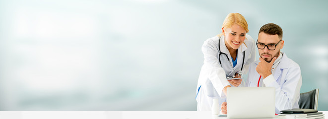 Doctor working with laptop computer at the office while having discussion with another doctor in the hospital. Medical healthcare and doctor service.