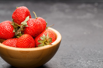 Photo close-up of ripe strawberry in wooden cup on black background