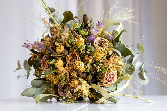 Close Up Of Wedding Bouquet Of Dried Flowers Lying On A White Table