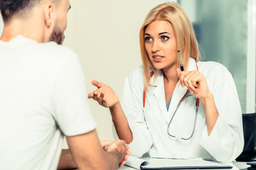 Woman doctor is talking to male patient in hospital office. Healthcare and medical service.