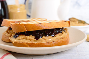 Toast with peanut butter and berry jam on a plate, tea. Nutritious breakfast.