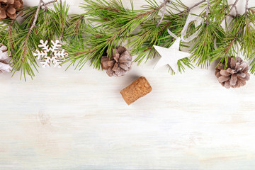 Christmas background with fir tree branches, cones, snow, xmas decorations and a champagne cork with a place for text, top shot