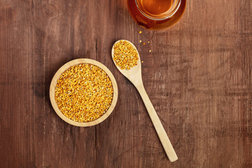 Healthy organic food. A top shot of pollen, a jar of honey, and a wooden spoon on a dark rustic background with copyspace