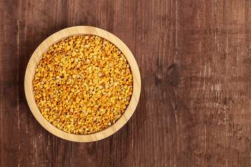 Healthy organic food. A top shot of pollen in a wooden bowl on a dark rustic background with copy space