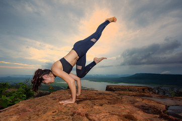 woman practice yoga training on the top peak of mountain, river and lake in background