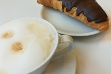 Fototapeta na wymiar Tasse Kaffee mit Milchschaum und ein Schokoladencroissant