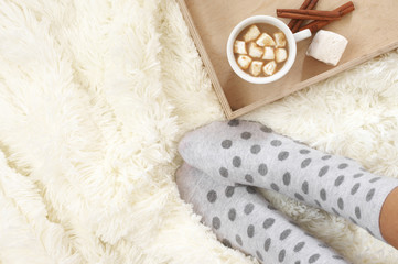 Woman feet in warm socks and hot chocolate