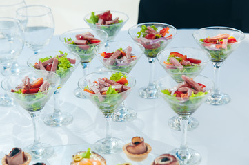 wine glasses with salad and meat snack at reception. catering snack service