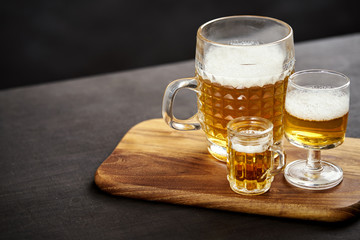 three golden delicious beers on an old black wooden table in a pub