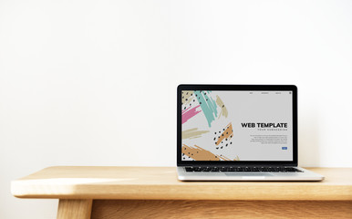 Laptop showing website template on a wooden table
